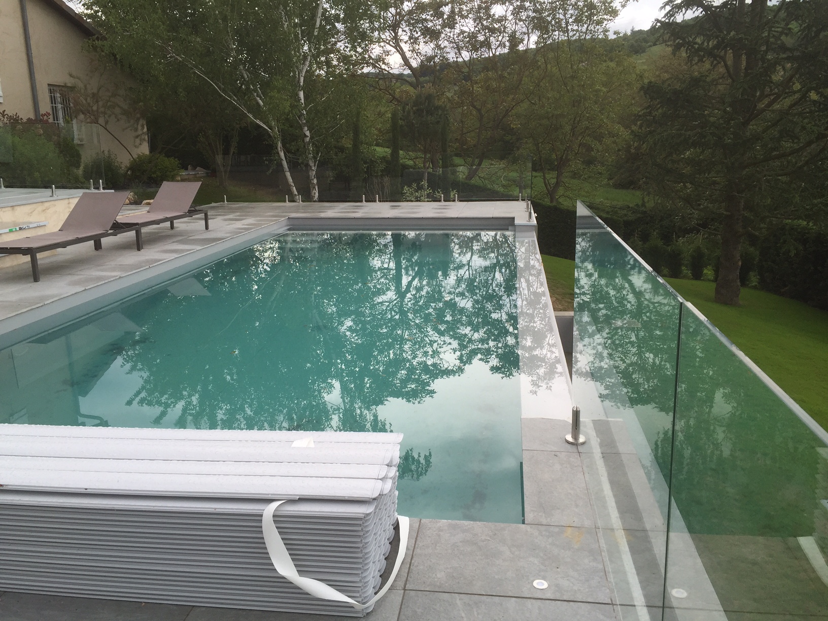 Barrière de piscine en verre sur pinces inox au sol Barrière de piscine en verre trempé 8,76 mm posée avec pinces inox au sol, conçue pour résister au chlore.