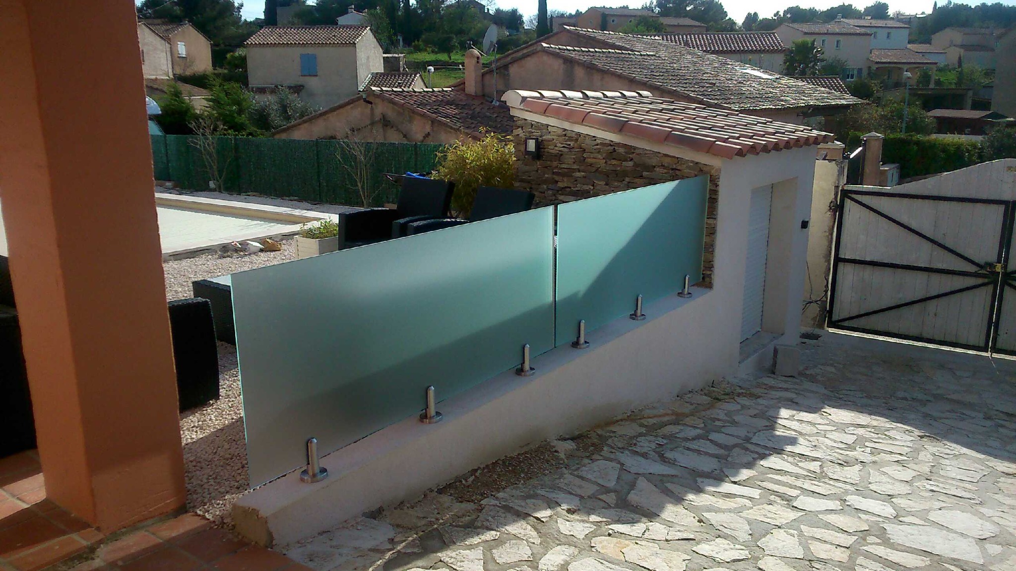 Brise-vue en verre dépoli sur muret béton avec pinces inox Brise-vue en verre dépoli installé sur muret béton avec pinces inox au sol, moderne et résistant en extérieur.