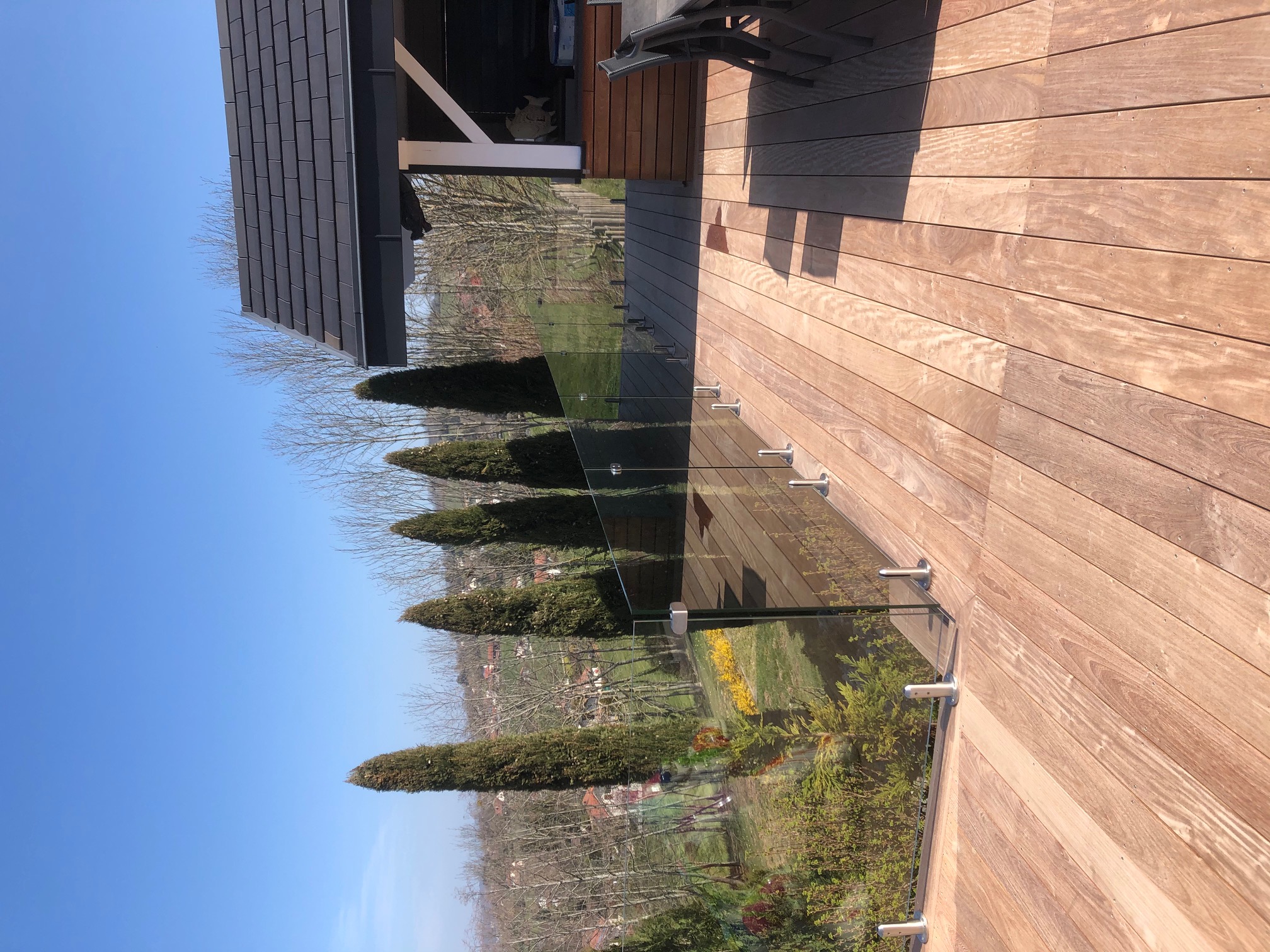 Garde-corps tout verre sur terrasse bois avec pinces inox au sol Garde-corps tout verre installé sur terrasse bois avec pinces inox au sol, sans montants et résistant en extérieur.