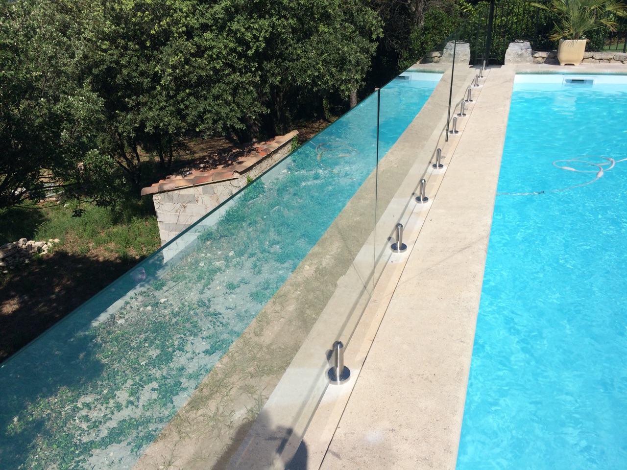 Protection en verre autour de piscine avec pinces inox au sol Protection en verre feuilleté 44/2 aux abords de piscine, fixée par pinces inox au sol et résistante au chlore.