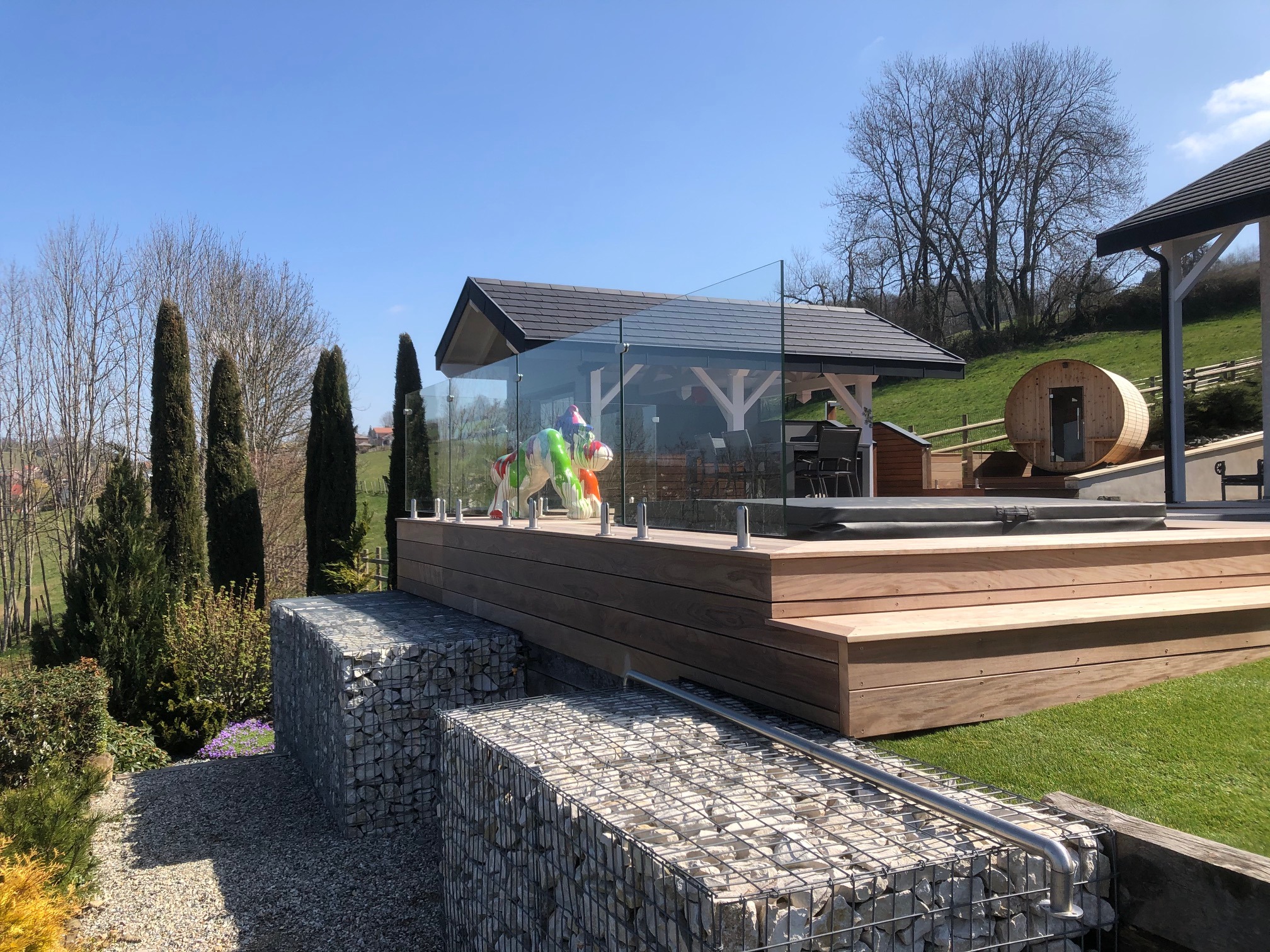 Rambarde tout verre sur terrasse bois avec pinces inox au sol Rambarde tout verre 44/2 installée sur terrasse bois avec pinces inox au sol, en extérieur et au design moderne.