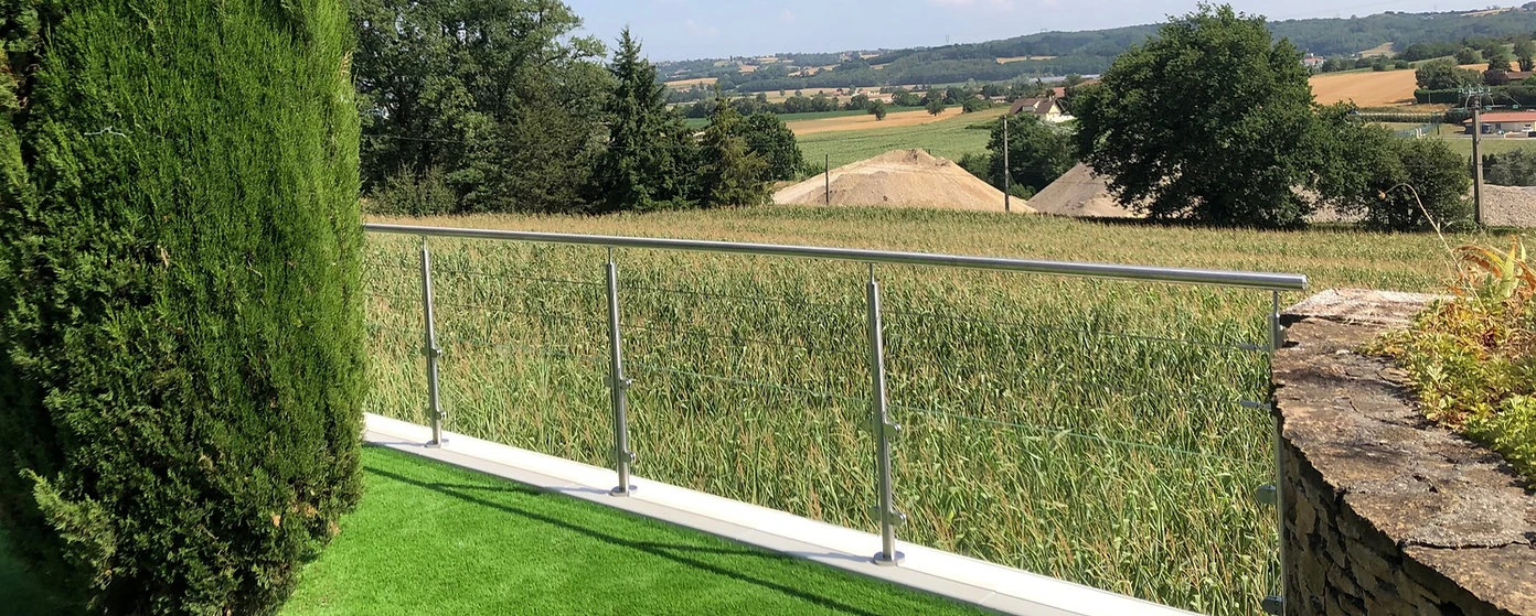 Détail de la jonction entre un panneau de verre et les câbles inox supérieurs