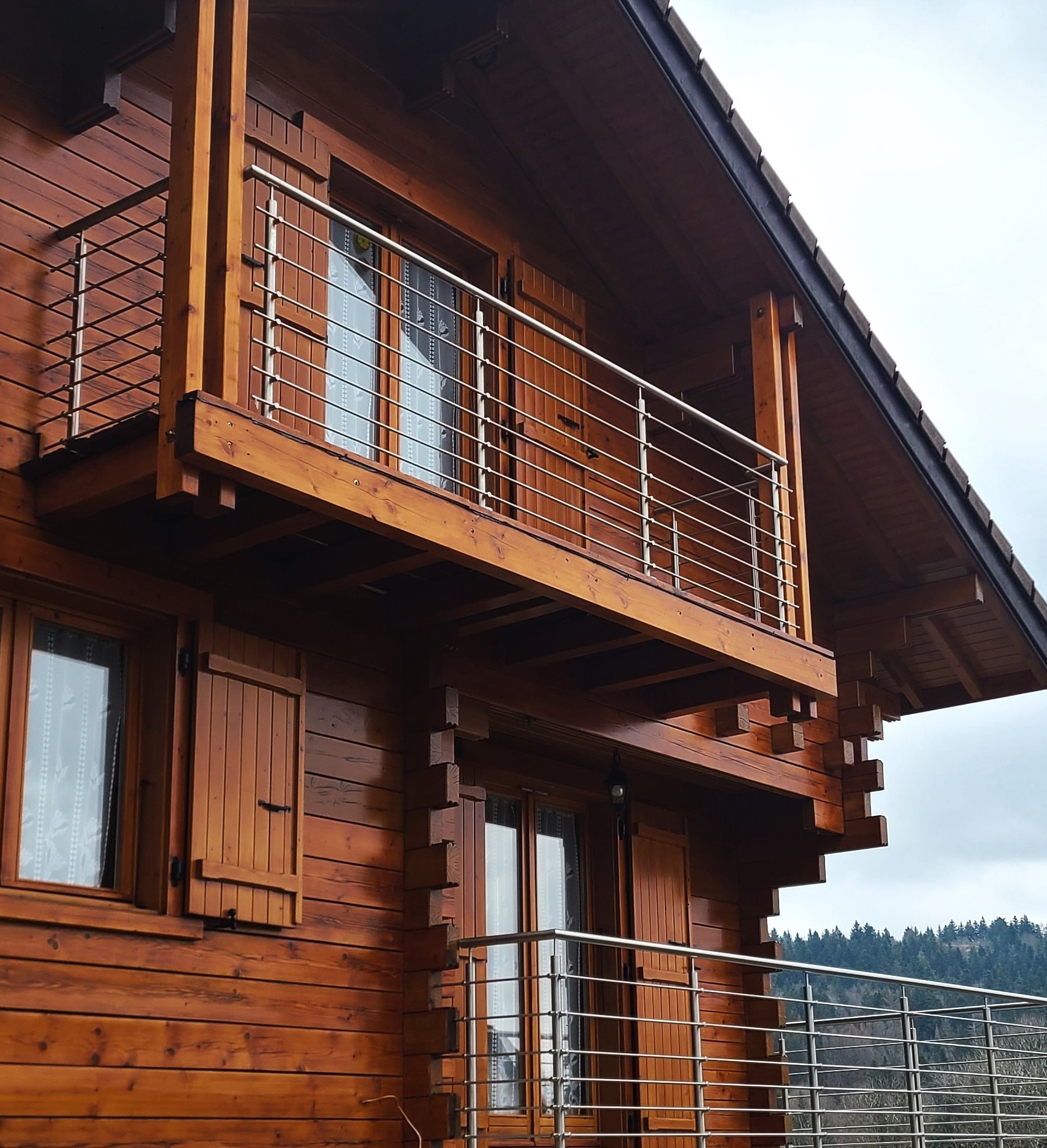 Vue d’une balustrade en inox à lisses pour balcon de chalet en bois, conçue pour résister en extérieur. Balustrade en inox à lisses installée sur un balcon de chalet en bois, résistante en extérieur et en pose à la française