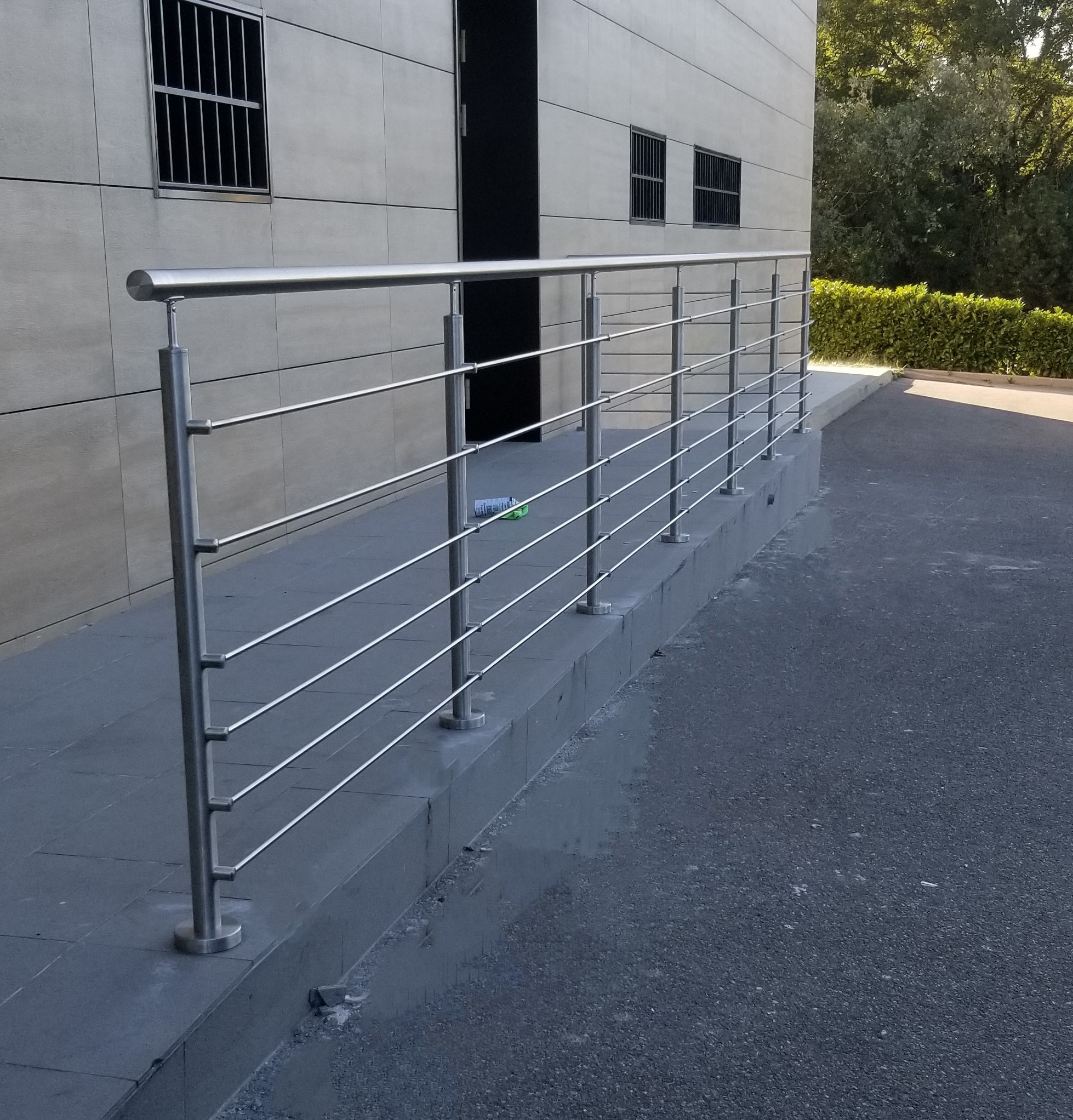 Aperçu d’une barrière de protection en inox à lisses pour atelier et dépôt, avec lisses horizontales. Barrière de protection en inox 304 à lisses horizontales pour atelier et dépôt, en extérieur et posée sur montants inox