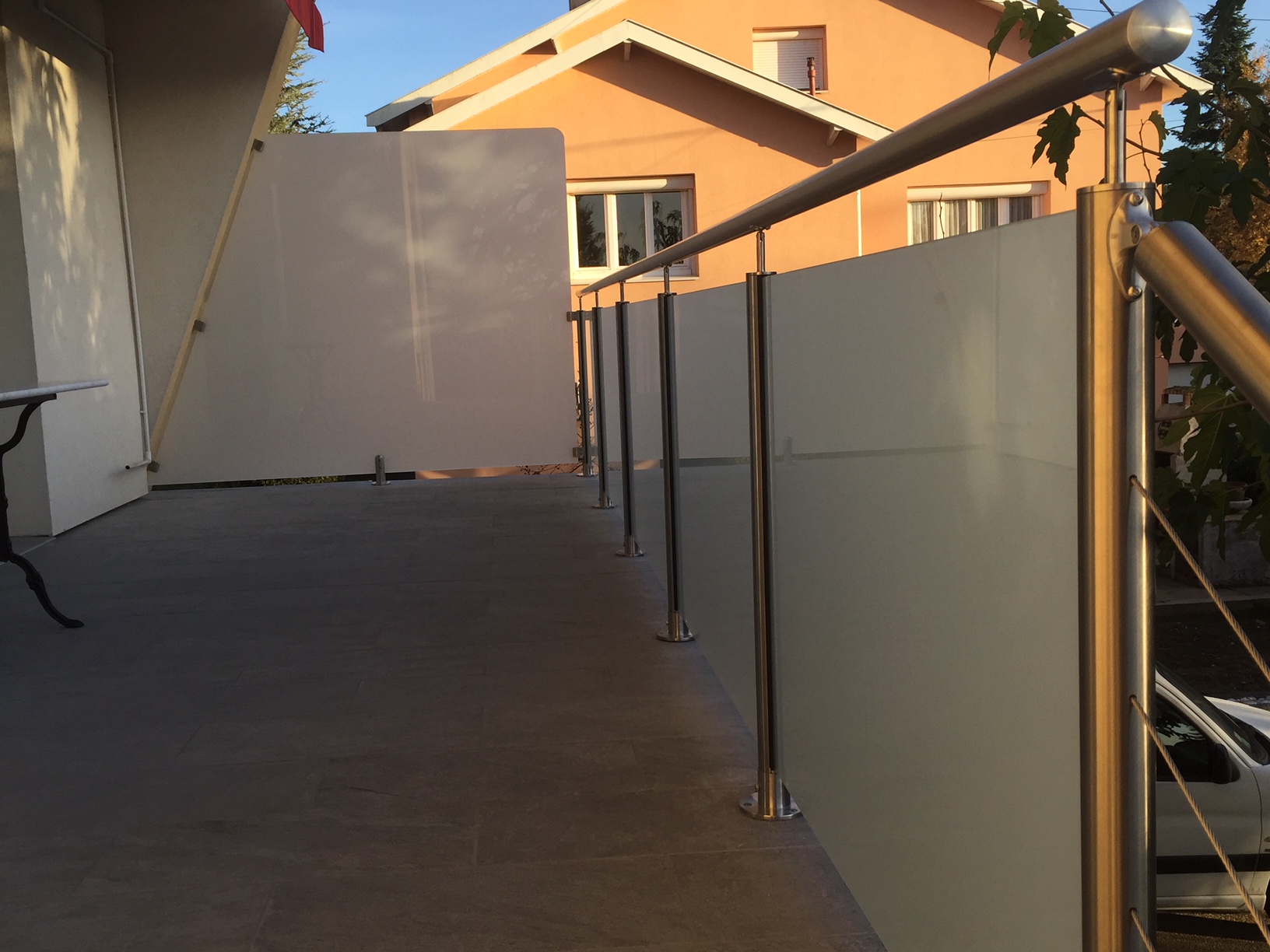 Vue d’un brise-vue en verre opale pour balcon, fixé par pinces à verre. Fabrication d’un brise-vue en verre opale trempé 8,76 mm pour balcon, en extérieur et avec pinces à verre