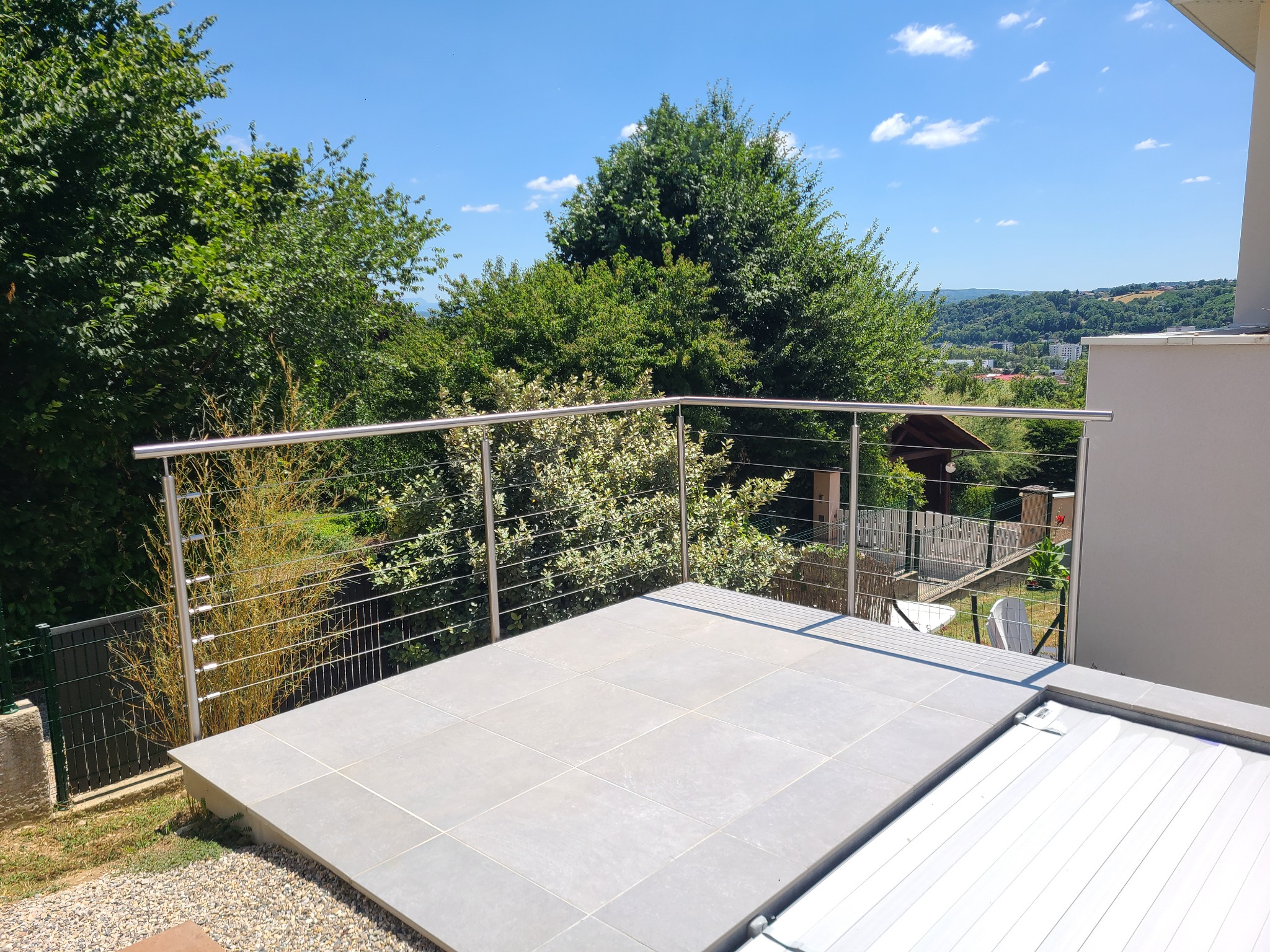 Détail d’un garde-corps en inox 304 à câbles pour piscine avec fixation latérale. Pose à l’anglaise d’un garde-corps en inox 304 à câbles pour piscine, avec tendeurs de câbles et protection piscine aux normes NF P90-306