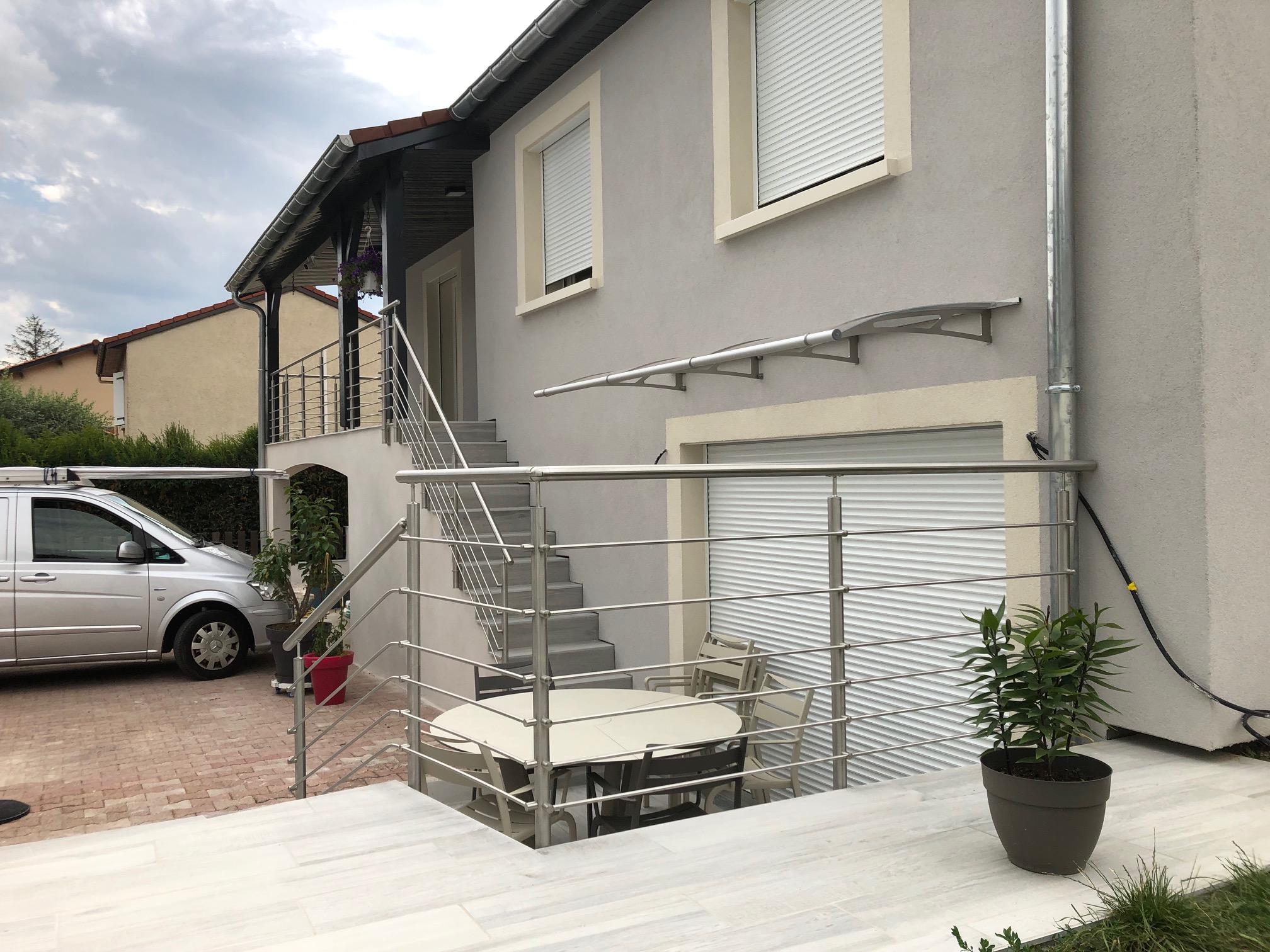Aperçu d’un garde-corps en inox à lisses pour escalier avec pose à l’anglaise, avec barre inox. Garde-corps en inox à lisses horizontales posé le long d’un escalier, en applique et avec barre inox