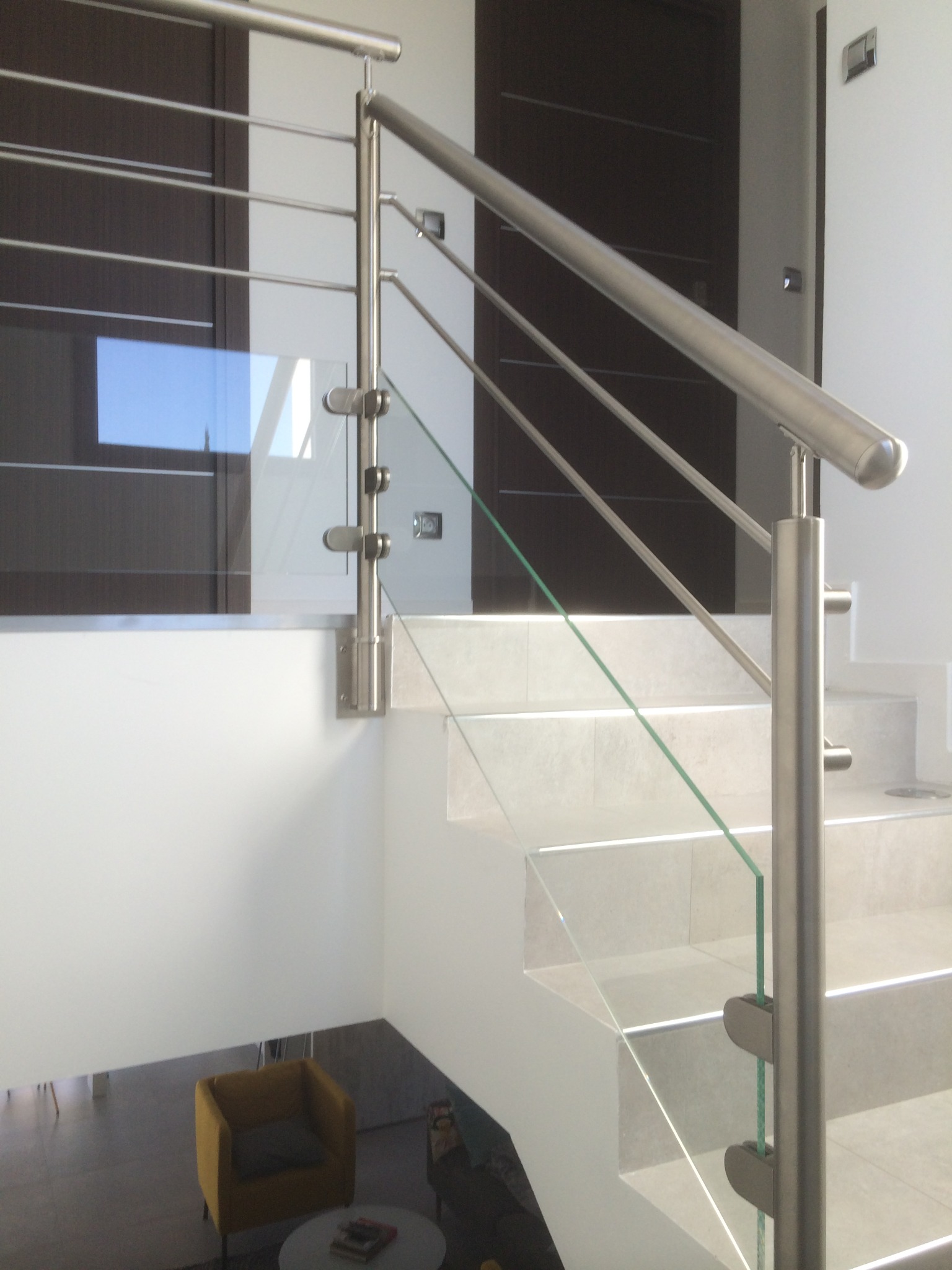 Aperçu d’un garde-corps en verre et lisses inox 304 pour escalier intérieur avec pose à l’anglaise. Garde-corps en verre et lisses en inox 304 posé le long d’un escalier