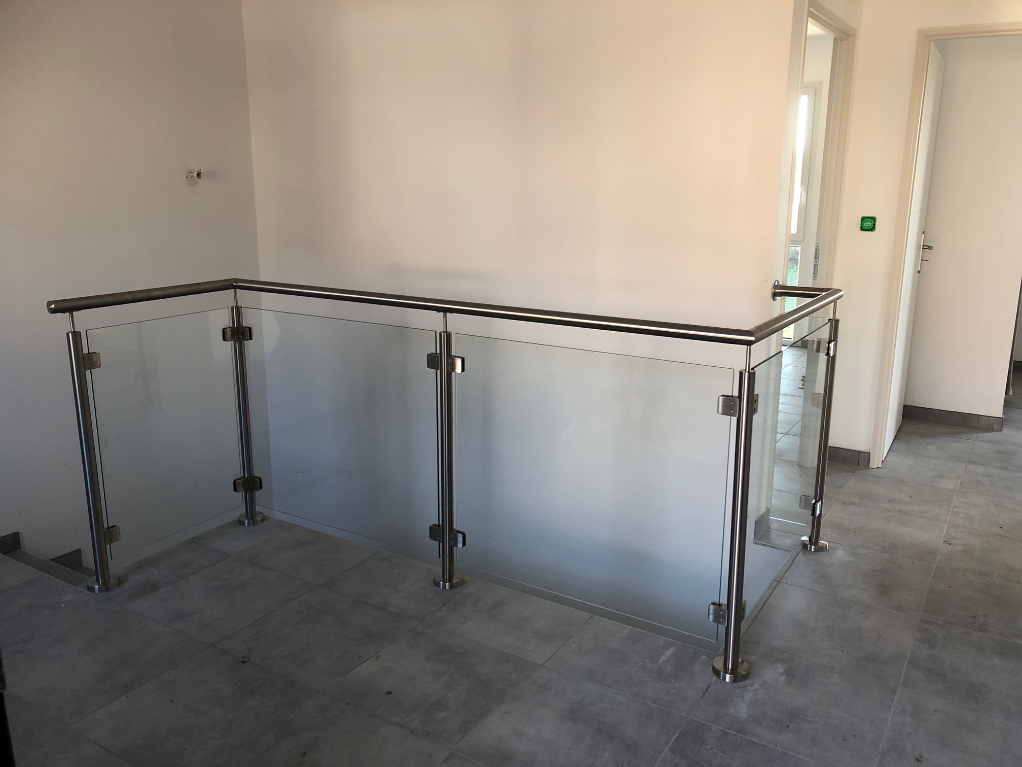Détail d’un garde-corps en verre 44/2 pour mezzanine intérieure. Garde-corps fabriqué en verre feuilleté 44/2 pour mezzanine intérieure