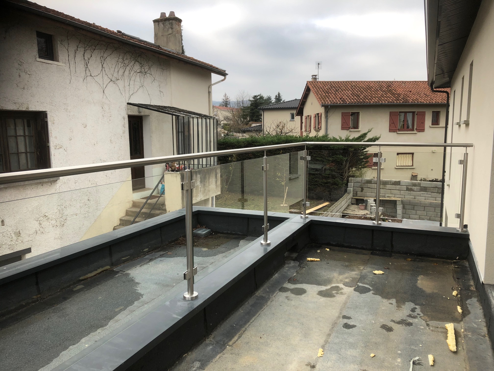 Garde-corps en verre trempé 8,76 mm posé sur acrotère de toit-terrasse avec couvertine alu RAL 7016, avec pinces inox et remplissage verre