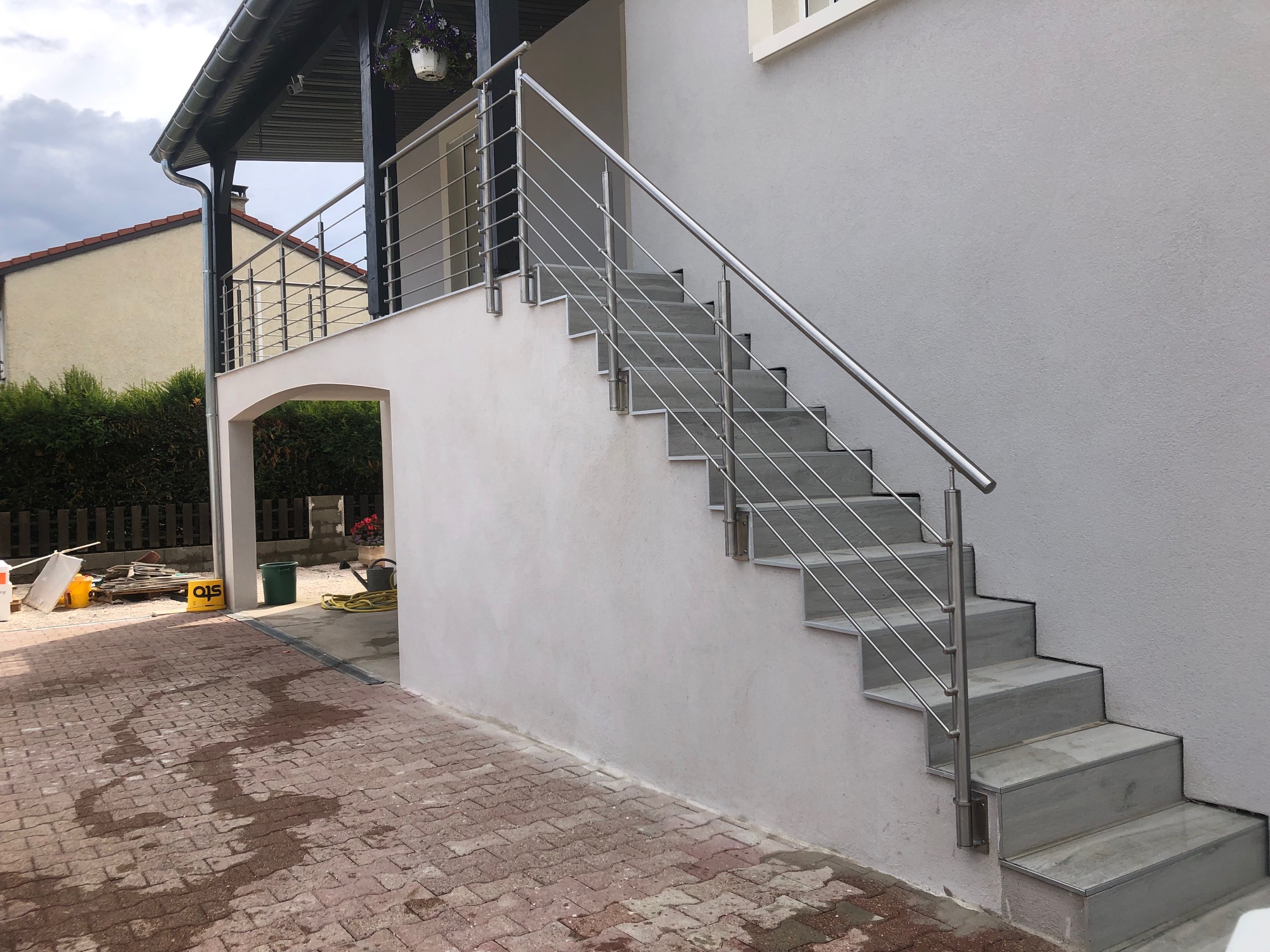 Aperçu d’une rambarde en inox à lisses pour escalier avec fixation latérale, avec montants inox. Rambarde en inox 316 à lisses pour escalier, sur montants inox et avec platine de fixation latérale et tubes inox horizontaux