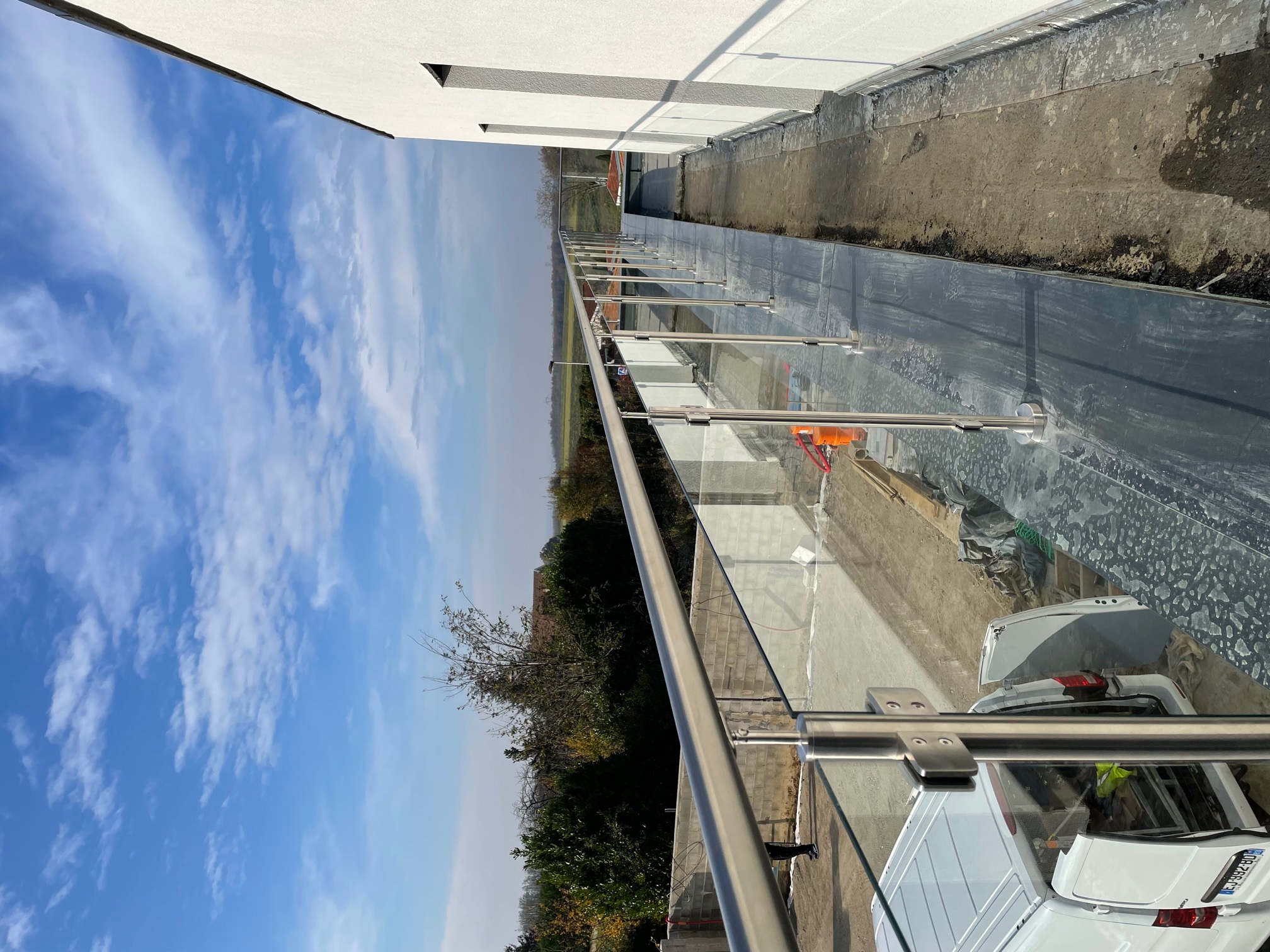 Vue d’une rambarde en verre 8,76 mm pour toit-terrasse sur acrotère avec couvertine aluminium RAL 7016. Rambarde en verre trempé 8,76 mm installée sur acrotère de toit-terrasse avec couvertine alu RAL 7016