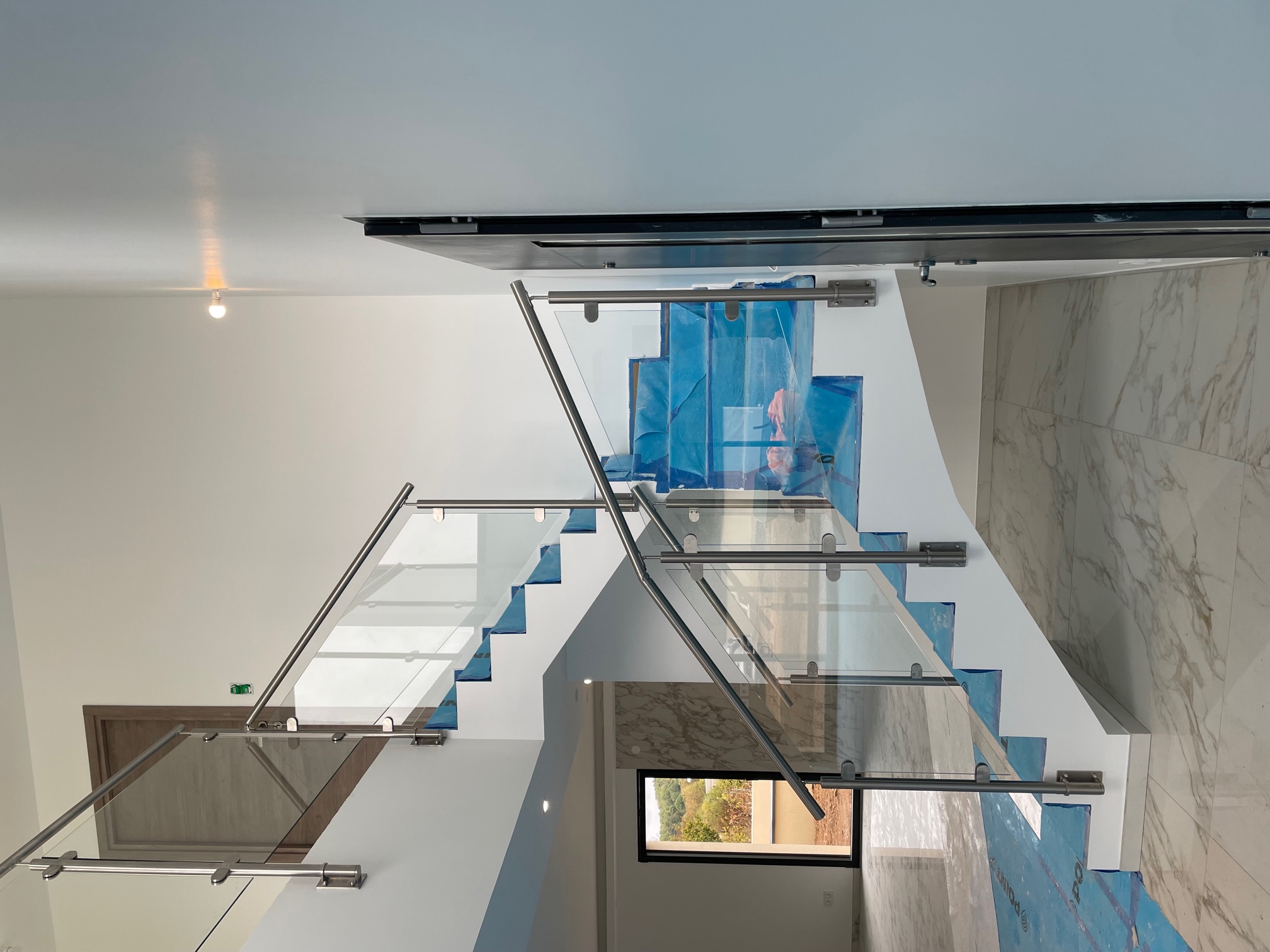 Vue d’une rambarde en verre 44/2 pour mezzanine intérieure avec fixation latérale. Rambarde en verre feuilleté 44/2 installée sur une mezzanine, posée en applique et avec structure en tube inox et remplissage verre